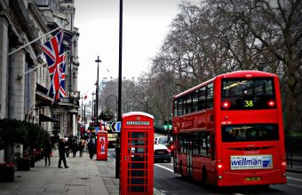 Classic London scene featuring a red double-decker bus and iconic phone booth on a busy city street.