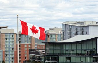 Canadian flag waving prominently in Halifax skyline with modern architecture.