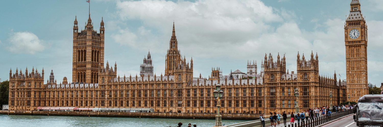A vibrant view of Westminster Palace and Big Ben from Thames showing tourists and traffic.