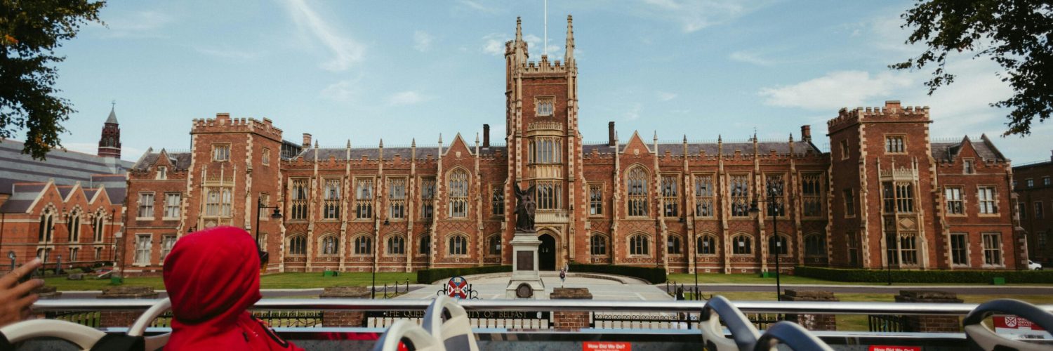 View of Queen's University Belfast captured from a tourist bus, showcasing stunning Gothic architecture and vibrant campus life.